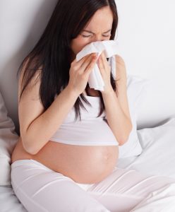 Sneezing pregnant woman on the bed