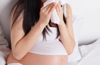 Sneezing pregnant woman on the bed
